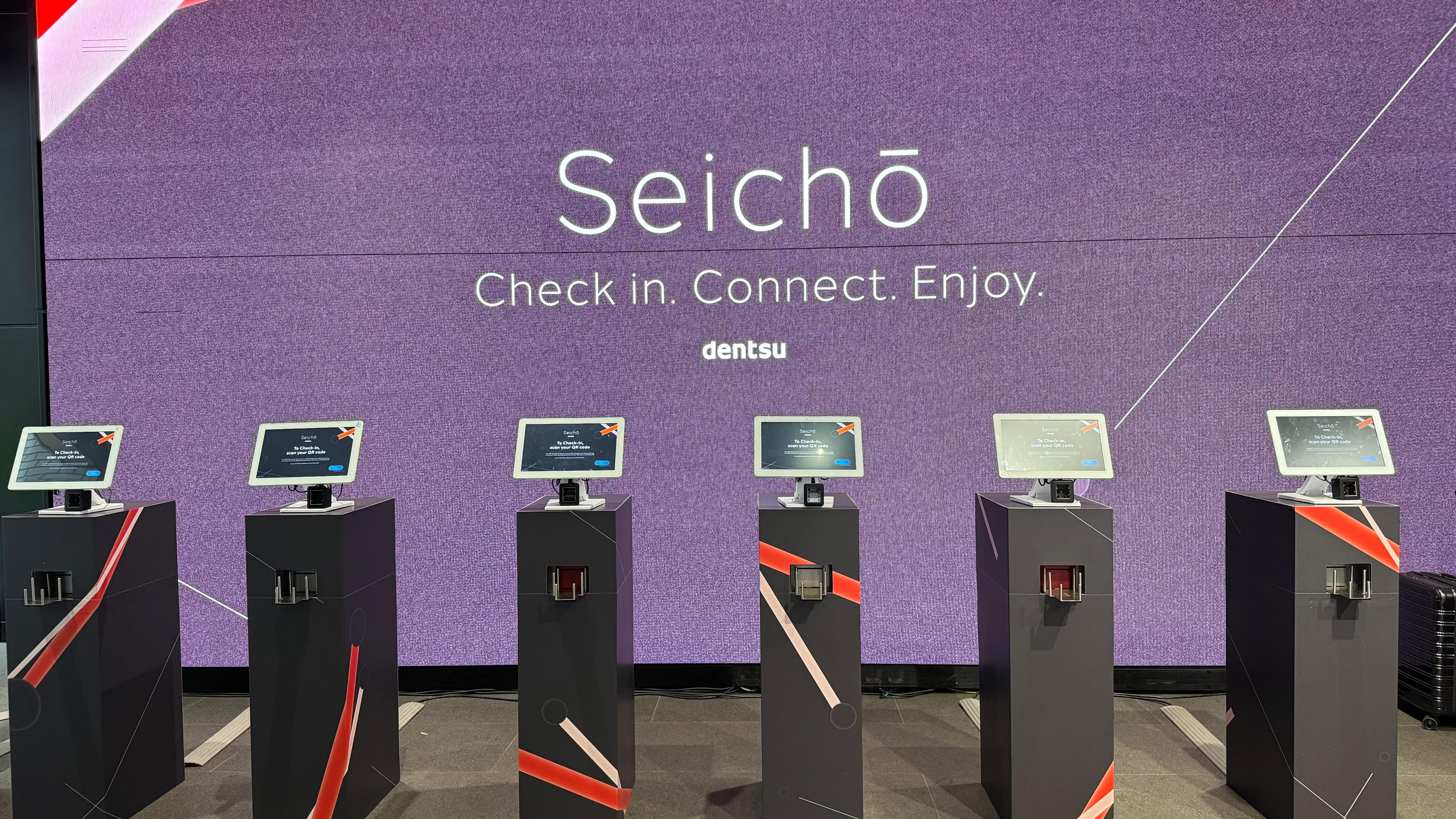 A row of fully branded Xtag freestanding check-in kiosks at a major event